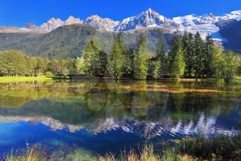 Mountain resort of Chamonix. Dreamlike beauty lake and park. In smooth water reflected snow-capped mountains