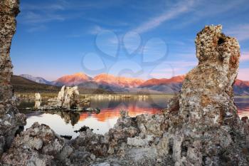  Outliers - bizarre limestone calcareous tufa formation on the smooth water of the lake. The magic of Mono Lake. Orange sunset