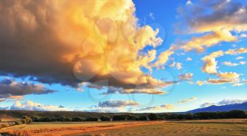 Improbably beautiful huge storm the cloud is shined with the sunset. The cloud hangs over the gravel road