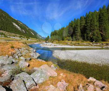 Headwaters Krimml waterfalls. Autumn creek shallow. Austrian Alps. The narrow stream flows between fields and forests