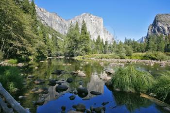 The magnificent Yosemite Valley. The huge granite monolith El Capitan and the blue sky reflected in the smooth waters of the river Mersed