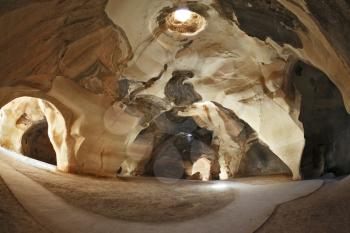 Israel National Park. Bell caves of Beit Guvrin.  Picturesque clay arches illuminated by the sun from the hole at the top and side entrances