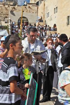 Jerusalem - October 16: the Sacred Western wall of the Temple. The Jewish family - the father in religious clothes with the son and a daughter prays with the prayer book in Sukkot October 16, 2011 in 