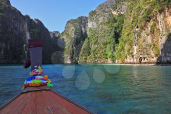 Thailand sightseeing boat sails in the picturesque bay. Bow is decorated with colorful and bright silk scarves