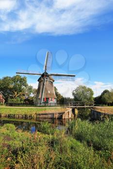 Rural landscape in the Netherlands. Verdant grove, quiet lake and a symbol of the country - windmills