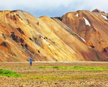 Pink and orange Mountains National Park Landmannalaugar in Iceland. At the foot of the mountains is worth admiring woman -turist. Snow remained on the mountains last year. 