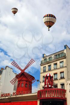 Two beautiful balloons flying over the Parisian cabaret Moulin Rouge. Red Tower, mill wings and the words Moulin Rouge.