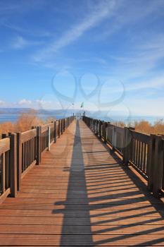 The long wooden pier on the shore of Lake Kinneret. Sunny spring day, sunset