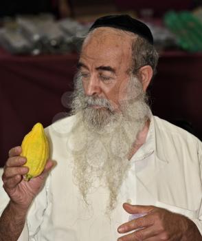BNEY-BRAK, ISRAEL - SEPTEMBER 17, 2013: Big market on the eve of the Jewish holiday of Sukkot. The handsome elderly man with gray-haired beard and in skullcap chooses a citrus