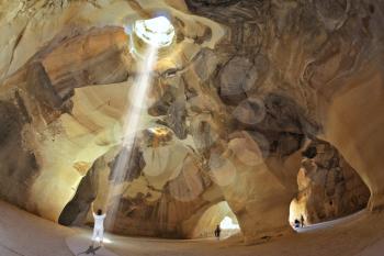 Yoga classes in the cave Beit Guvrin, Israel.  Woman in white performs asana Sun salutation. 