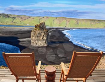 Rock in the sand. Cape Dirholaey in southern Iceland. On a coastal rock delivered comfortable wooden loungers