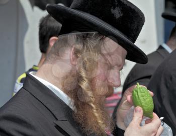 JERUSALEM, ISRAEL - SEPTEMBER 18, 2013: Traditional market before the holiday of Sukkot. The religious Jew with red beard and long side curls carefully examines ritual citrus