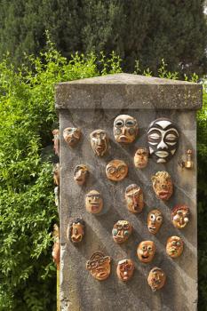 Stone curbstone in a garden, decorated ceramic ritual masks