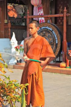 CHIANG MAI, THAILAND - APRIL 14, 2011: Boy in orange clothes of Buddhist monk from hose watering the flowers
