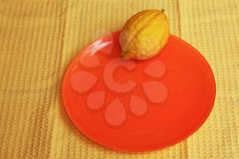 Jewish holiday of Sukkot. Ritual fruit - etrog on the orange plate and yellow napkin 