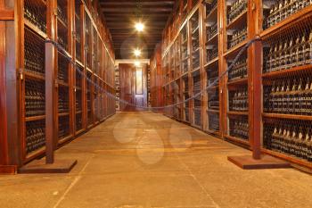 FUNCHAL, MADEIRA - OCTOBER 08, 2011: Museum - repository of expensive vintage wine Madera. Long rows of shelves made of mahogany. The shelves are made with sweet wine bottles Madera