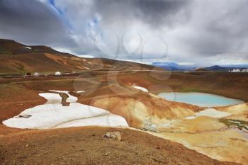 July in Iceland. Krafla lake in the crater of an extinct volcano. On the banks are last year's snow fields