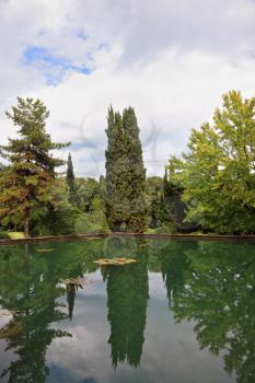 Beautiful park garden Sigurta in northern Italy. Cypress reflected in a pond