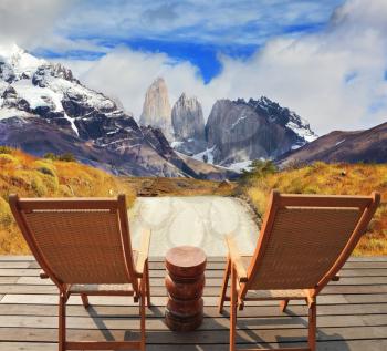 Wooden chairs in the park Torres del Paine. On the horizon is visible snow-covered rocky mountain. Pleasant holiday in Chile