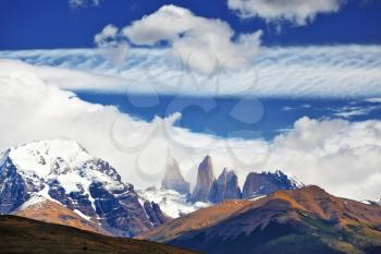 Fabulous harmony of the national park Torres del Paine in Chile. Three rocks Torres are surrounded by picturesque clouds 