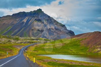  The road passes through the picturesque landscape in the mountains and lakes. Cloud Iceland in the summer