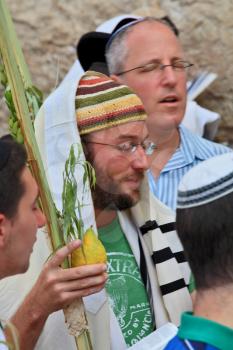 JERUSALEM, ISRAEL - SEPTEMBER 20, 2013: The Western Wall of the Temple in Jerusalem. Young religious Jew in a knitted skullcap and talite with citrus-etrog praying in the morning of Sukkot