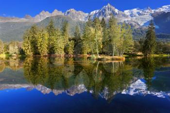 Dreamlike beauty lake and park. In smooth water reflected snow-capped mountains surrounding the mountain resort of Chamonix