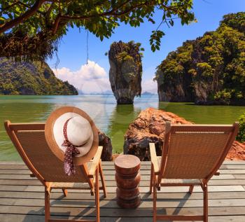 Exotic rest in Thailand. The coast of the gulf in the Andaman Sea. Two convenient chaise lounges and an elegant hat on one