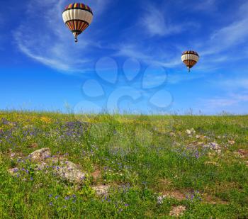 Two huge and beautiful balloons fly over a flowering field. Flowering Golan Heights on a sunny day
