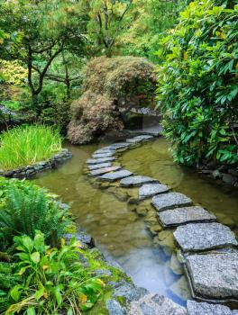  Decorative private garden on Vancouver Island in Canada - Butchart Gardens. The track of the stones in the water in the Japanese part of the garden