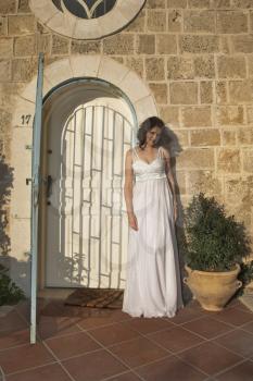 The beautiful bride in a white dress on a background of ancient walls of ancient city