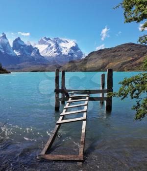 Boat dock on Lake Pehoe. The National Park Torres del Paine, Chile. On the opposite side of the lake majestic snow-capped cliffs of Los Kuernos.