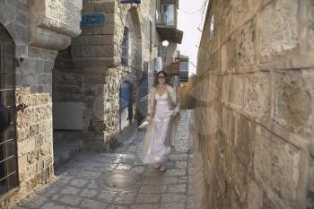  The beautiful bride smiling runs on narrow street of old city.