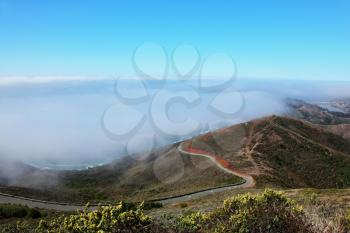 Morning fog at hilly coast of Pacific ocean and road