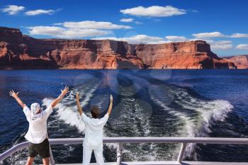 Woman and man in the stern boat delighted nature. Artificial lake Powell on the Colorado River, USA. The lake is surrounded by picturesque beaches of the orange sandstone