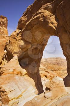 Natural erosive arch in hills from red sandstone in desert Arava