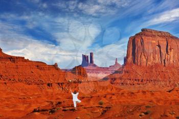 Navajo Reservation in the US. Red Desert and rocks - mitts sandstone. Woman in white performs asana Tree