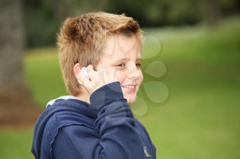 The beautiful European  boy in park talks on a cellular telephone