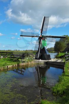 The ancient windmill is reflected in water of a small pond. Clear autumn day in the Netherlands