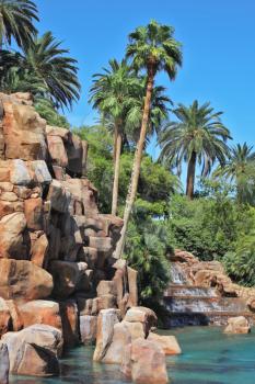 Multistage stone fountain surrounded by tropical vegetation and palm trees. The spectacular cascade fountain. 