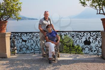 Nice elderly couple tourists poses a photographer in the park near Lake Maggiore
