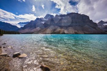 The cold waters of the lake surrounded by scenic Canadian Rocky Mountains. Azure Bow Lake in Banff National Park