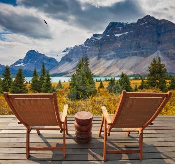 On the wooden platform there are two deckchairs beside a beautiful lake. Cold autumn day in the Rocky Mountains of Canada