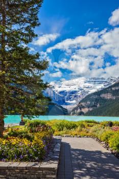 The picturesque promenade on the glacial Lake Louise. The emerald waters of the lake surrounded by mountains, glaciers and pine forests. Banff National Park, Rocky Mountains, Canada