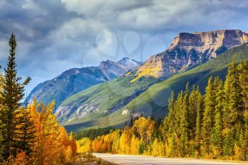  Canada, Alberta, Rocky Mountains. Highway in Banff National Park. Mountains and colorful autumn forest illuminated by the sunset