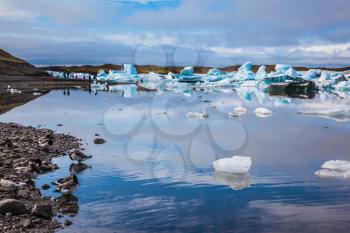 Summer vacation in Iceland. Ice lagoon in July. Icebergs and ice floes are reflected in the mirrored water of ocean Bay