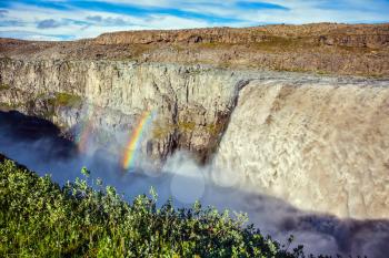 Iceland in July, lush rainbow in the water foam. Magnificent and huge waterfall Dettifoss