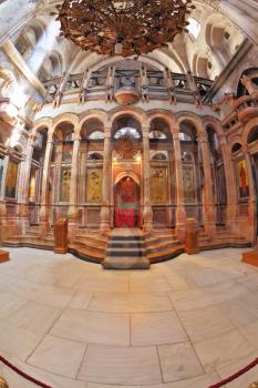 The huge marble hall in the Holy Sepulchre lit bright sun. On the walls of the hall paintings on biblical themes. Entry to the altar of the draped red curtain