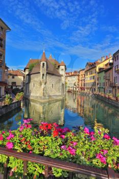 Charming old town of Annecy in Provence. Clear early in the morning. Bastion prison, reflected in the water channel. Bridge over the canal is decorated with flowers
