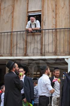Bnei Brak - September 22: Picturesque scene: A group of young religious Jews in black velvet skullcaps on the market to choose citron Sukkot. An elderly white-bearded rabbi with a smile watching them 